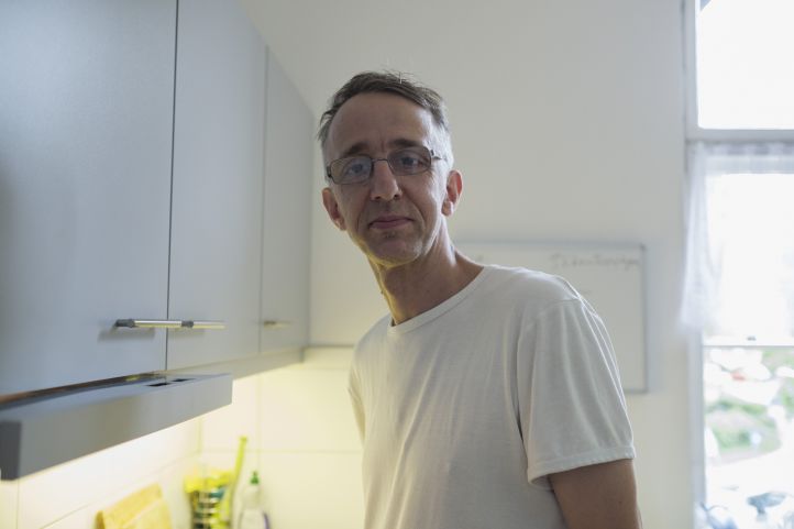 Ein Mann mit Brille im weißen T-Shirt steht in einer Küche