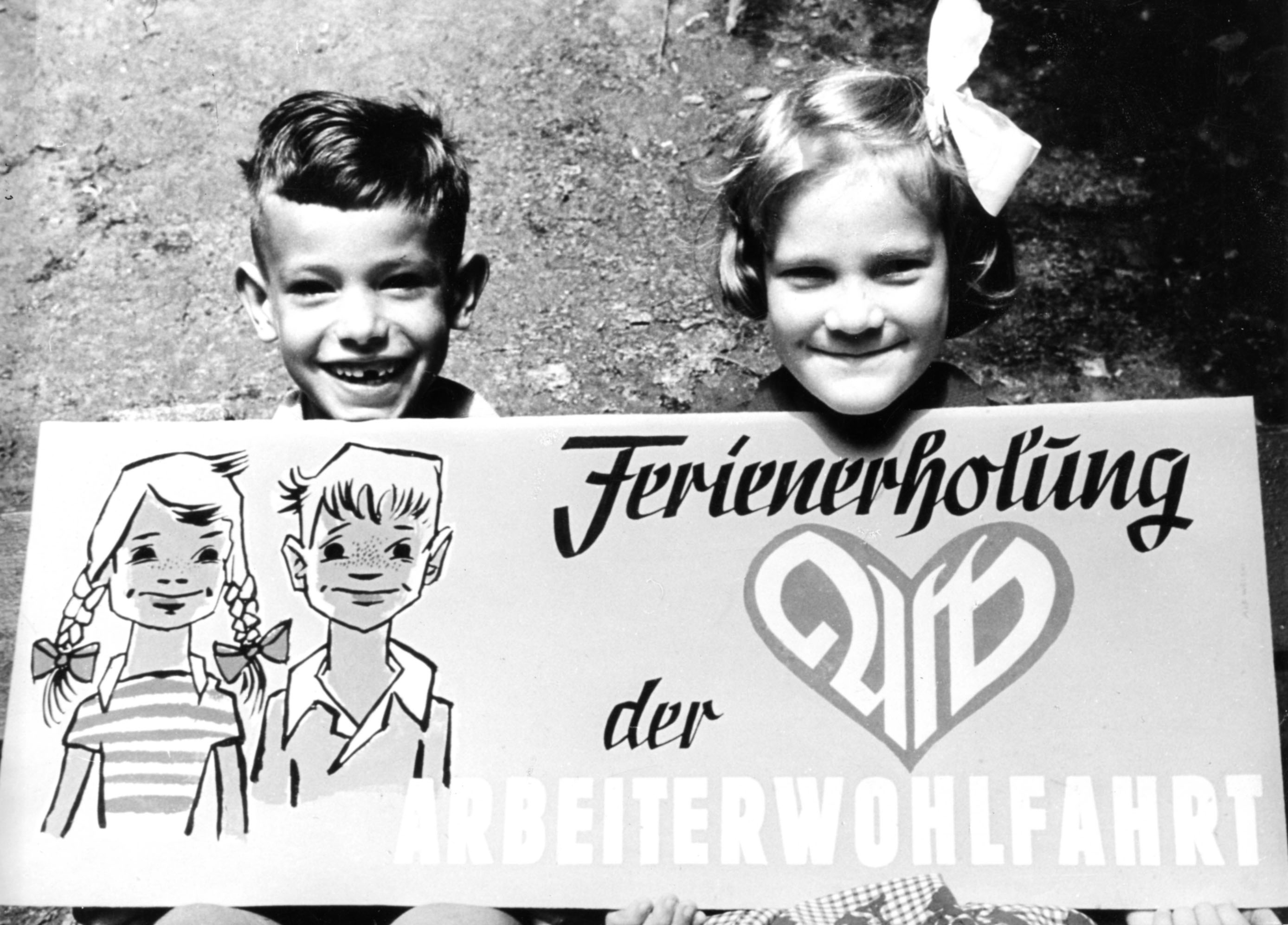 Ferienfreizeit der AWO historisches BIld mit lachenden Kindern einem Jungen und einem Mädchen und einem Plakat Ferienerholung