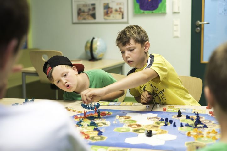 Das Bild zeigt zwei Kinder, die gemeinsam ein Brettspiel spielen.