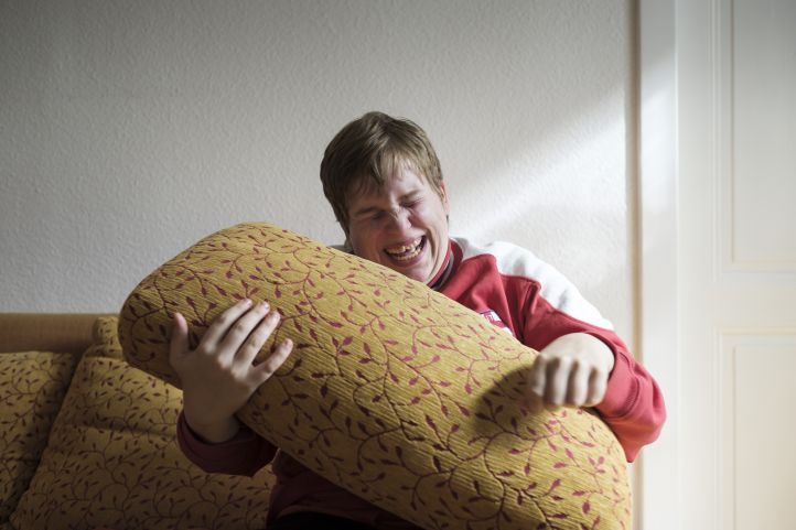 Eine Frau hält ein Sofakissen und lacht herzhaft
