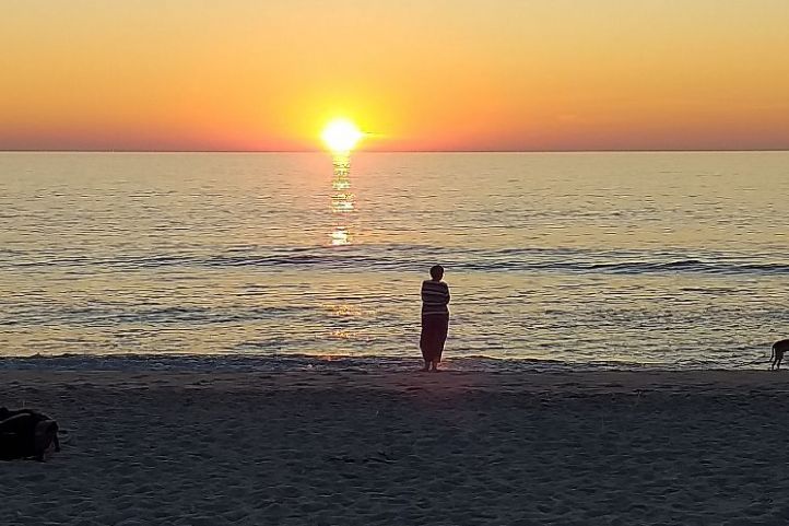 Frau vor Sonnenuntergang am Meer
