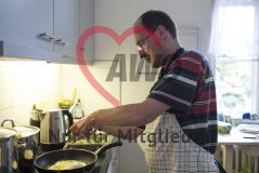 Ein Mann steht in einer Küche und bereitet Spiegeleier vor