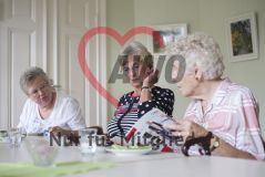 Drei Seniorinnen sitzen an einem Tisch und unterhalten sich über das, was sie in einem Katalog sehen