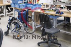 Arbeitsplatz in einer Werkstatt mit Schreibstuhl und Rollstuhl