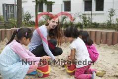 Eine junge Frau spielt mit Kindern im Sandkasten