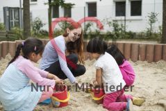 Eine junge Frau spielt mit Kindern im Sandkasten