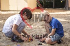 zwei Jungs spielen im Sandkasten mit Autos
