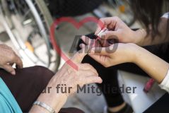 Eine Frau lackiert einer alten Frau Seniorin die Fingernägel