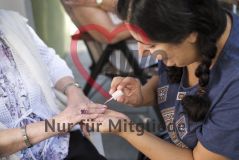 Eine Frau lackiert einer alten Frau Seniorin die Fingernägel