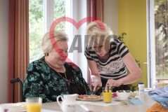 Eine Frau hilft einer Frau im Rollstuhl beim Essen