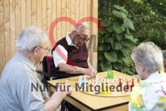 Mehrere alte Frauen und Männer Seniorinnen und Senioren spielen draußen ein Brettspiel
