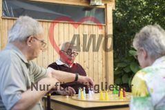 Mehrere alte Frauen und Männer Seniorinnen und Senioren spielen draußen ein Brettspiel