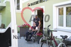 Ein Mann bringt einen alten Mann Senior im Rollstuhl aus einer Tagesbetruung der AWO
