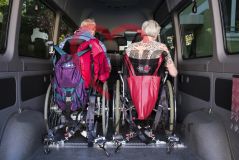 Zwei alte Menschen Senior und Seniorin in Rollstühlen sitzen in einem Transporter