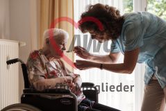 Eine Frau hilft einer alten Frau Seniorin im Rollstuhl beim Essen