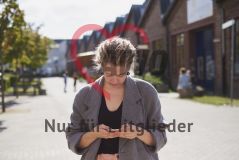 Eine junge Frau steht draußen und tippt auf dem Handy Smartphone