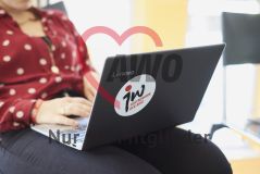 Eine junge Frau sitzt mit einem Laptop Notebook Rechner auf dem Schoß Aufkleber jw Jugendwerk der AWO