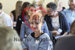Eine junge Frau nimmt an einer Veranstaltung und lächelt in die Kamera