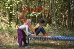 zwei Kinder im Wald, auf einer Bank spielend