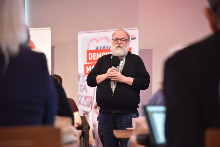 Ein mann spricht in ein Mikrofon mit AWO-Bannern im Hintergrund