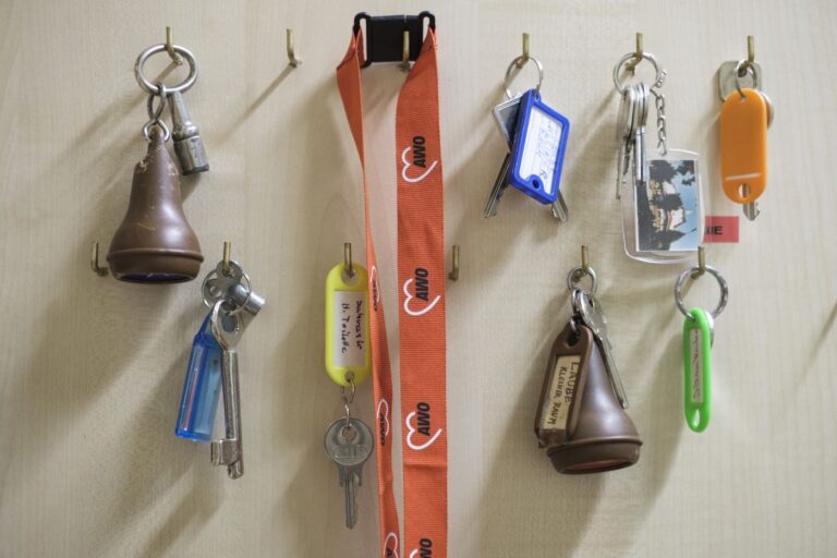 Mehrere Schlüsselbunde hängen an Haken an einer Holzwand, einer davon mit AWO-Logo.