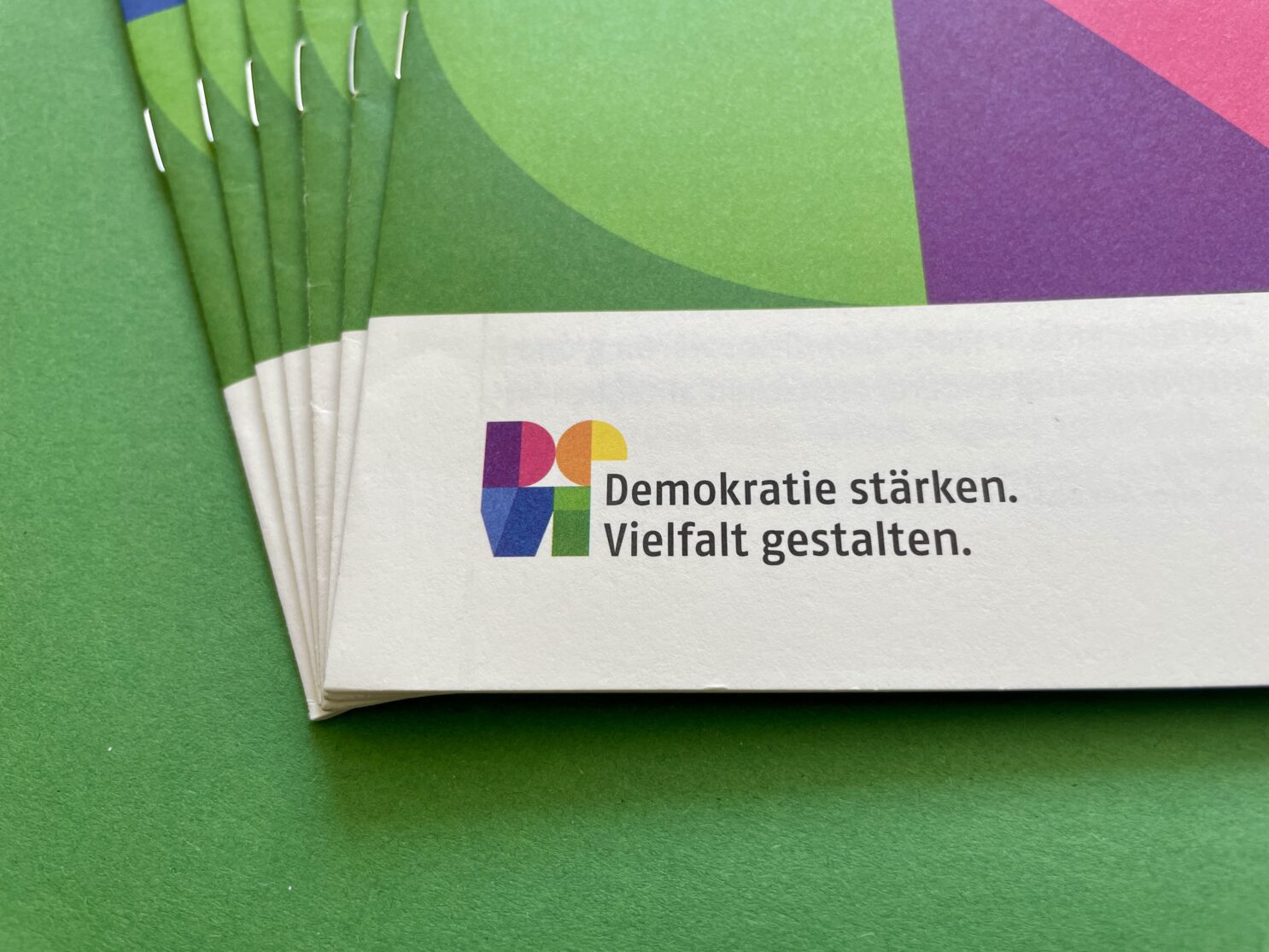 Broschürenstapel mit dem Logo von DEVI und dem Slogan „Demokratie stärken. Vielfalt gestalten.“