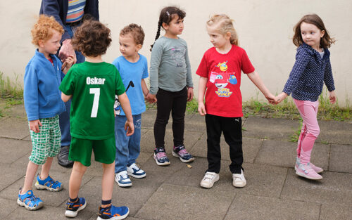 sechs Kita-Kinder, die sich an den Händen halten