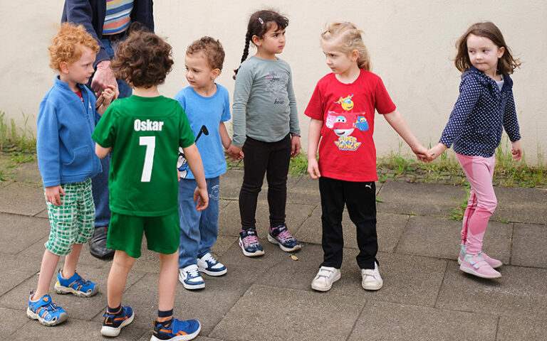 sechs Kita-Kinder, die sich an den Händen halten