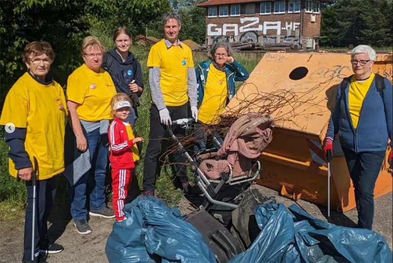 Sechs Erwachsene und ein Kind in gelben Shirts bei einer Müll-Sammelaktion