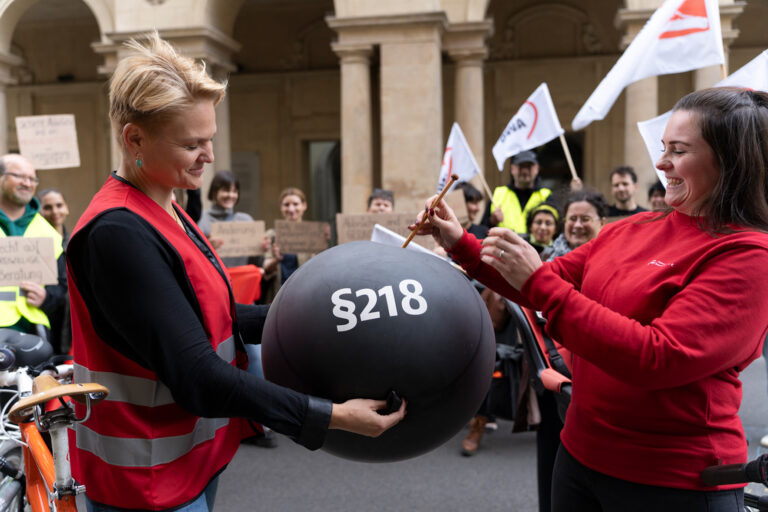Frauen von ZFF und AWO lassen einen schwarzen Ballon mit Aufschrift "§218" zerplatzen.