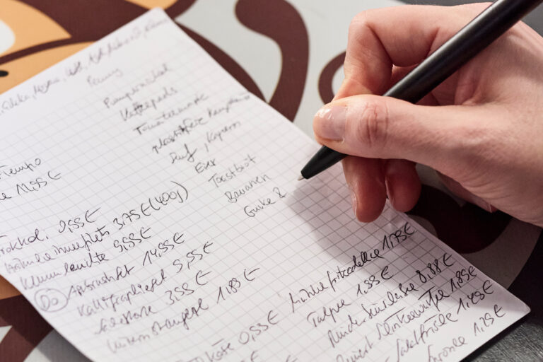 Nahaufnahme eines handschriftlichen Zettels, auf dem Ausgaben für Lebensmittel notiert sind