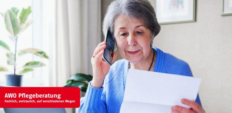 Eine ältere Frau hält ein Telefon an ihr Ohr, während sie ein Papierdokument liest.