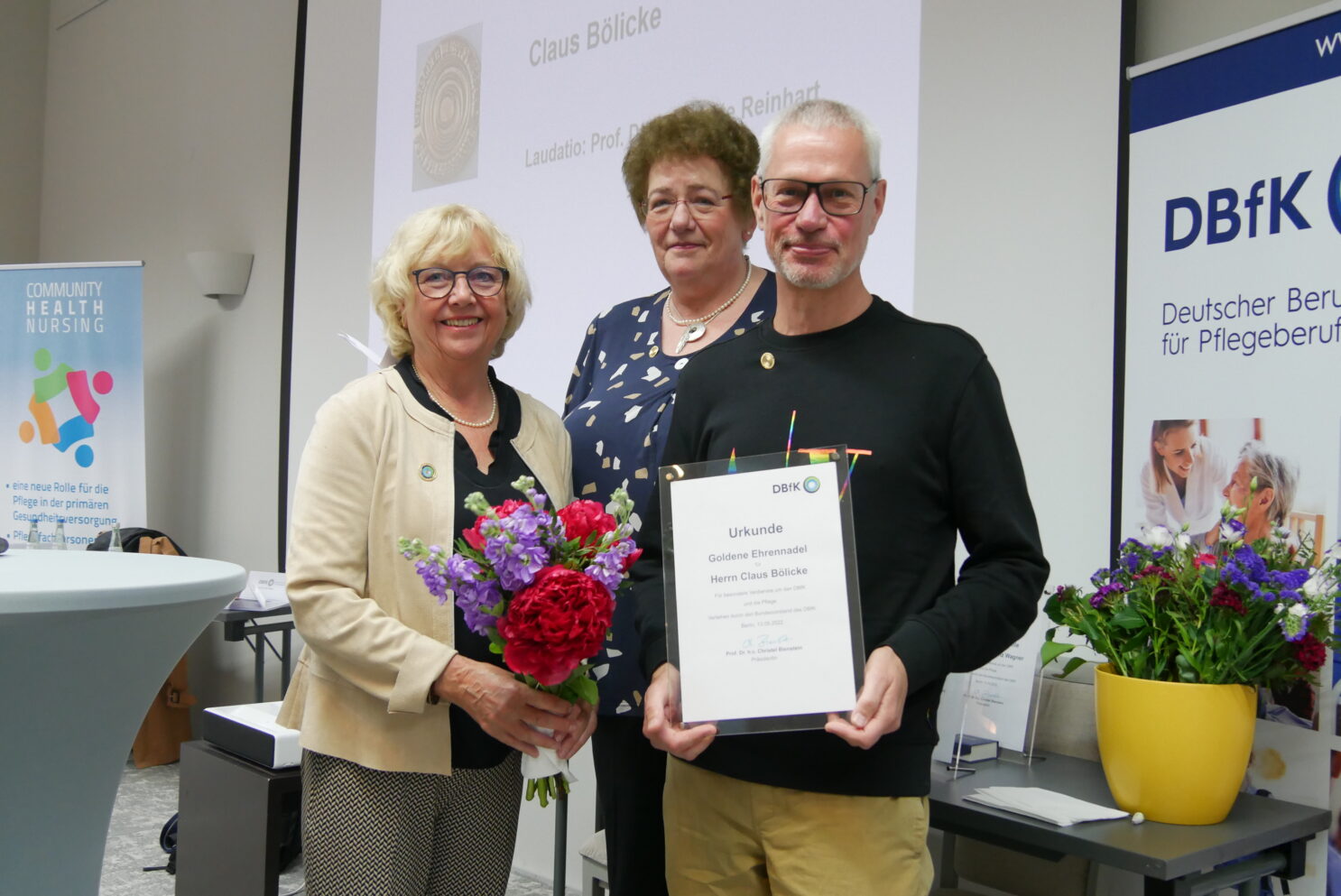 Drei Menschen von der Health Nursing Community bei der Verleihung für die"Goldene Ehrennadel".