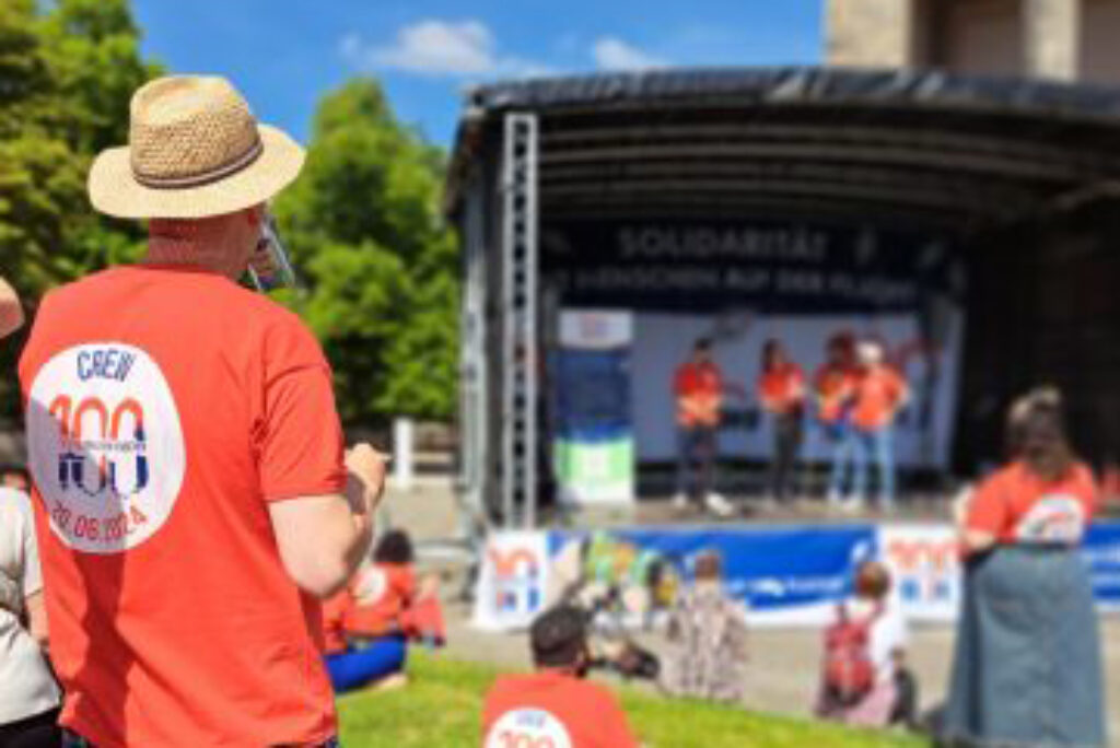 Menschen vor einer Bühne bei der Aktion "100 Boote - 100 Millionen Menschen"
