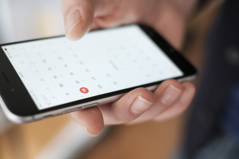 Smartphone mit Kalenderapp in der Hand eines Menschen