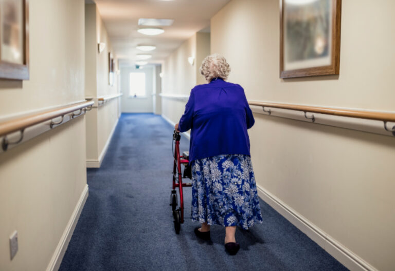 Seniorin mit Rollator auf dem Flur eines Pflegeheims