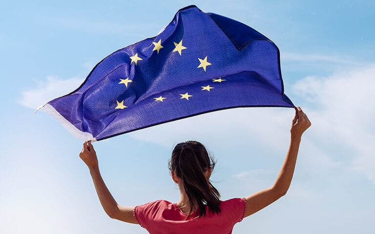 Mädchen schwenkt Europa-Flagge über dem Kopf