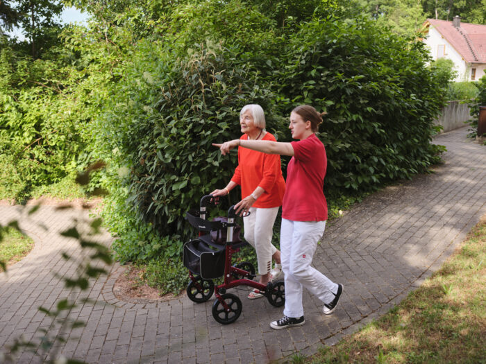 Pflegerin geht mit Seniorin spazieren
