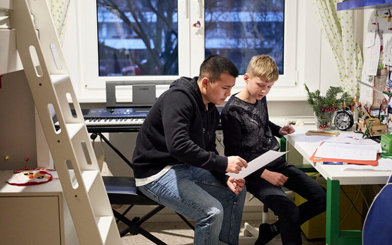 Teenager am Schreibtisch in seinem Zimmer in einer Mietwohnung