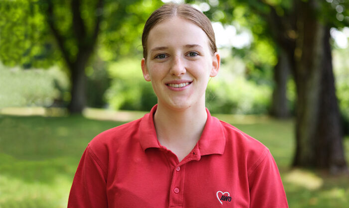 Lächelnde jung Frau im roten Poloshirt mit AWO-Logo