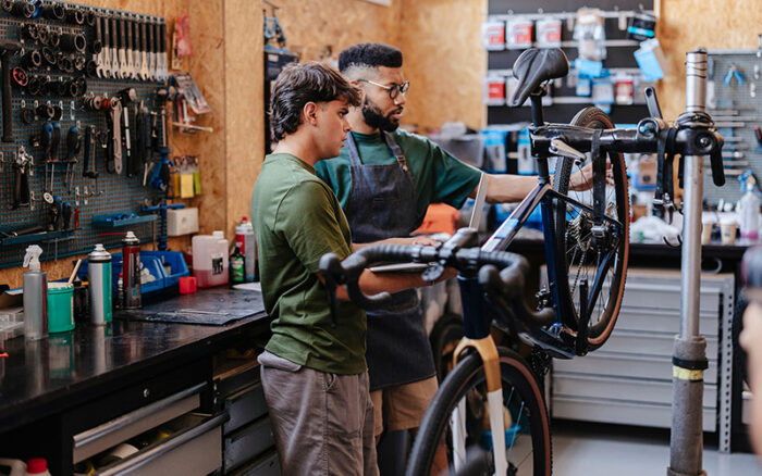 Zwei Männer reparieren in einer Werkstatt ein Fahrrad.
