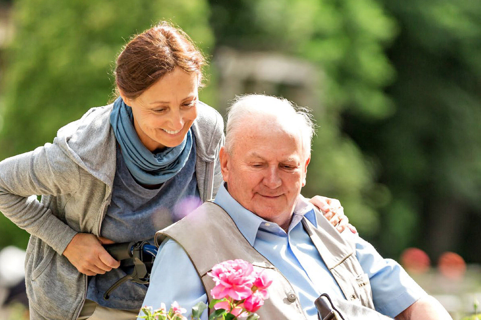 Frau schiebt Senior im Rollstuhl