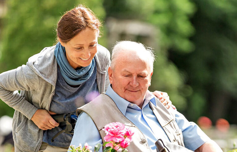 Frau schiebt Senior im Rollstuhl