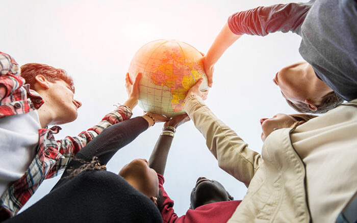 Fünf Teenager verschiedener Kulturen halten einen Globus in die Höhe.