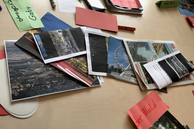 Auf einem Tisch liegen Fotos, die beschriftet wurden, z.B. mit "der Wald".