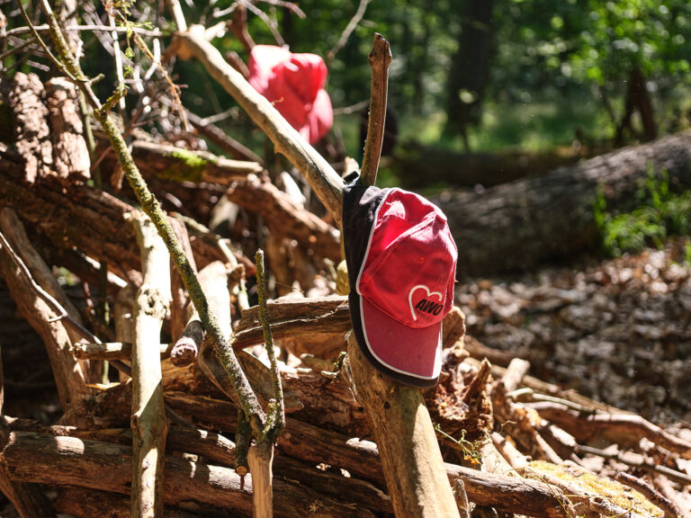 Ein AWO-Käppi hängt an einem Ast im wald.