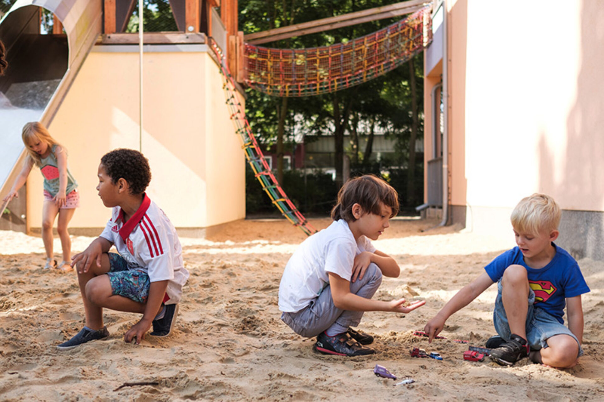 Vier Kinder spielen auf einem Spielplatz im Sand.
