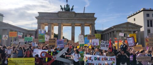 Eine große Menschenmenge steht vor dem Brandenburger Tor und hält viele Plakate und Banner in die Luft.