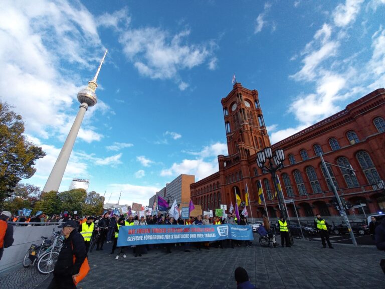 Berlin Alexanderplatz und rotes Rathaus. AWO Schild wird in die Luft gehalten.