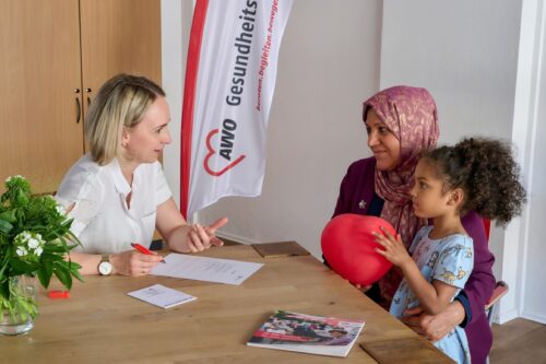 Gesundheitstreff in Hamburg, Frauen sitzen am Tisch, Kind mit Luftballon, Muslima, AWO, Kopftuch